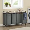 A laundry room scene with a multi-compartment laundry hamper, a washing machine, and decorative items on a shelf. Produktbild-Vorschau