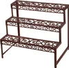 A three-tiered plant stand made of dark brown metal with an ornate scroll design. Anteprima dell’immagine prodotto