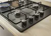 A close-up shot of a black gas hob with four burners, set into a wooden countertop. Anteprima dell’immagine prodotto