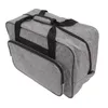 A gray sewing machine storage bag with black handles and zippers, shown from a slightly elevated side angle against a white background. Náhľad obrázku produktu