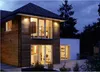 A modern house exterior at dusk, with lights on inside. Produktbild-Vorschau