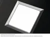 A close-up, angled view of a square, illuminated lighting element with a silver frame against a black background. Voir les images du produit