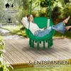 A woman is relaxing in a green hanging chair on a wooden deck, using a laptop. Podgląd zdjęcia produktu