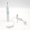 A white electric toothbrush, its charging base, and a replacement brush head are arranged on a white surface. Produktbild-Vorschau