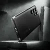 A black phone case is shown in a dramatic, angled shot, appearing to be placed on a rough, stone-like surface with a dark, textured background. The lighting is dramatic, creating strong shadows and highlights. Anteprima dell’immagine prodotto