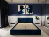 A bedroom with a dark blue upholstered bed frame, two abstract paintings on the wall, and two white nightstands. Produktbild-Vorschau