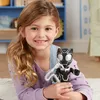 A young girl is lying on the floor, holding a Black Panther action figure. Produktbild-Vorschau