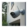 A security camera mounted on the exterior wall of a building, with greenery in the background. Podgląd zdjęcia produktu