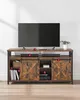A television stand with a television on top, a soundbar, and several items on the shelves. Produktbild-Vorschau