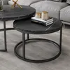 A close-up view of two round nesting coffee tables with black marble tops and black metal frames, placed on a gray carpet next to a gray sofa. Voir les images du produit