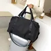 A person holding a black duffel bag over a silver suitcase. Voir les images du produit