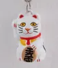 A close-up studio shot of a white Maneki-neko (lucky cat) keychain. Produktbild-Vorschau