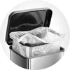 A close-up view of the top of a stainless steel trash can with a black lid open, revealing a clear plastic trash bag inside. Produktbild-Vorschau