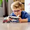 A young boy playing with a toy space shuttle transporter. Voir les images du produit