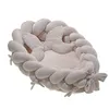 A baby nest with braided sides and a crescent-shaped pillow, presented on a white background. Náhled obrázku produktu