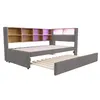 A gray upholstered daybed with a pull-out trundle bed and a built-in wooden bookshelf headboard, shown against a white background. Podgląd zdjęcia produktu