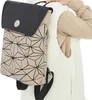 A person wearing a sweater and a white vest is seen from the chest up, carrying a backpack. Produktbild-Vorschau