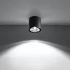 A black cylindrical ceiling light fixture is mounted on a white ceiling, casting a bright light downwards. Produktbild-Vorschau