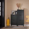 A hallway or entryway scene featuring a black shoe cabinet, a yellow umbrella stand, and a wooden chair. Produktbild-Vorschau