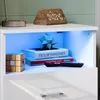 A close-up view of a white, high-gloss nightstand with LED lighting, displaying decorative items and books. Produktbild-Vorschau