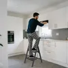 A man is using a step stool in a modern kitchen. Voir les images du produit