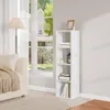A white bookshelf with items on it, next to a window with a view of houses and trees. Produktbild-Vorschau