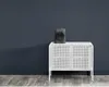 A black heater sits on top of a white cabinet against a dark gray wall. Voir les images du produit