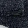 A close-up view of a dark gray, high-pile rug with a textured surface and a small button or clasp visible. Produktbild-Vorschau