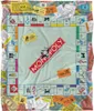 A Monopoly board game scene depicted on a blanket, with money and game cards scattered around. Produktbild-Vorschau
