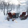 A cozy outdoor seating area in a snowy forest with a fire pit and chairs. Produktbild-Vorschau