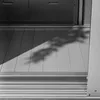 A close-up view of the bottom section of a metal storage cabinet, showing the base and a shadow of foliage on the floor. Anteprima dell’immagine prodotto