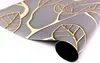 A rolled-up piece of wallpaper with a gray background and a gold leaf pattern. Produktbild-Vorschau