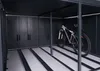 Interior view of a dark gray bicycle garage with multiple storage compartments and a bicycle parked on a sliding track. Náhled obrázku produktu