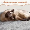 A Siamese cat is lying on a soft, grey surface, with text overlaying the top of the image. Produktbild-Vorschau