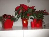 Christmas decorations including poinsettias, ornaments, and candles on a white shelf. Anteprima dell’immagine prodotto