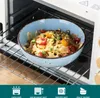 A blue bowl of pasta with vegetables and cheese is placed on a rack inside an oven. Náhled obrázku produktu