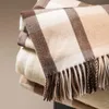 A close-up view of a folded plaid blanket with fringe. Náhled obrázku produktu