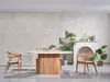 A dining table and chairs set in a well-lit room with decorative plants and a fireplace. Produktbild-Vorschau