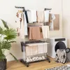 A multi-tiered clothes drying rack filled with laundry, placed next to a washing machine in a laundry room setting. Produktbild-Vorschau