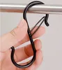 A hand holding a black S-hook. Produktbild-Vorschau
