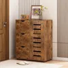 A wooden shoe cabinet with drawers and slatted doors, placed in a room near a door and a wall. Podgląd zdjęcia produktu