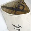Close-up view of the top opening of a beige laundry hamper with a black mesh lining and a drawstring. Produktbild-Vorschau
