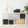 A white cube shelving unit filled with various storage boxes, books, and decorative items. Produktbild-Vorschau