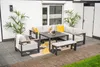An outdoor lounge set with a sectional sofa, armchair, table, and bench on a patio with plants. Produktbild-Vorschau