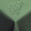 A close-up view of a dark green tablecloth with water droplets on it, showcasing its water-repellent feature. Produktbild-Vorschau