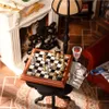 A miniature room scene with a fireplace, a lamp, a chess set, and a glass of red liquid. Náhľad obrázku produktu
