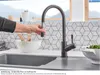 A hand is shown using a bronze kitchen faucet with a pull-down sprayer. Produktbild-Vorschau