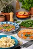 A collection of decorative plates, pasta, and fresh greens arranged on a countertop, suggesting a culinary theme. Produktbild-Vorschau