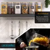 A kitchen scene showing glass storage jars filled with food items, ladles hanging on a rack, and a person pouring pasta into a pot. Náhled obrázku produktu