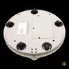 The underside of a white, circular electronic device with wheels, against a black background. Voir les images du produit